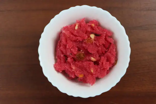 Sooji beet root halwa is a Sugar beet-Semolina based sweet dessert pudding from India. Garnished with Cashew/almond nuts and Served in a bowl, festival food, celebration