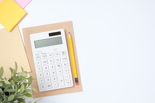 top view working desk with calculator and notebook on white table background