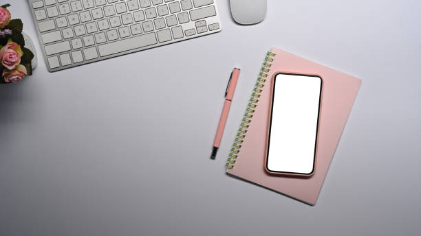 istock Top view smart phone, notebook, pen and wireless keyboard on white table. 1365067217