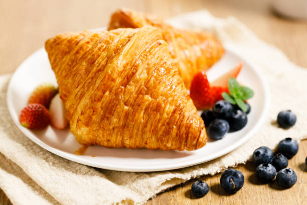 istock breakfast with croissants and fresh berries on wooden table. 1365069028