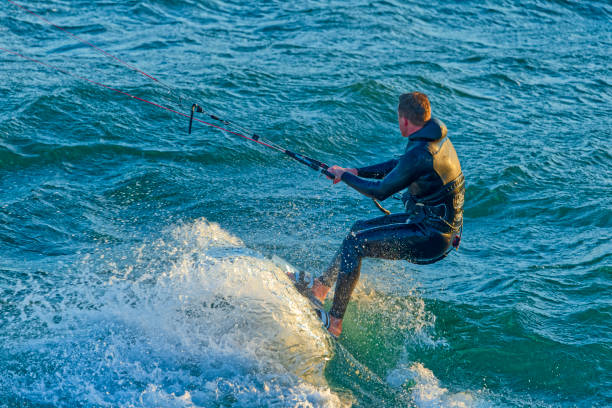 Small group of kitesurfer on the North Sea on a sunny day during. Extreme sport, the beach of in Scheveningen in the background. The Hague, Netherlands.