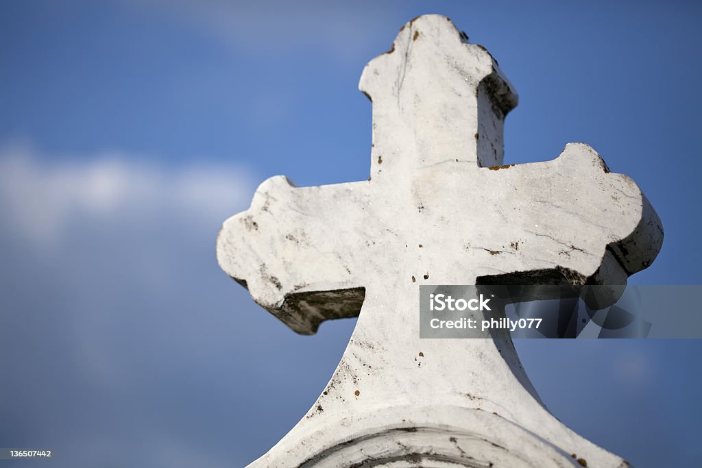 Stone cross at cemetary Stone cross against blue sky at cemetery Blue Stock Photo
