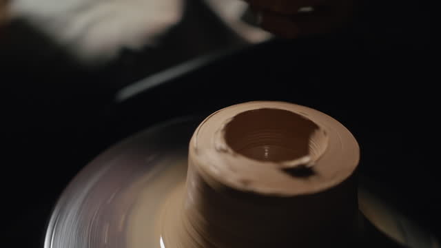 Artisan male hands shaping and cutting jug from a clay on a potter's wheel