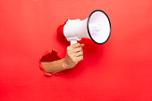 man hand holding a megaphone on red  background