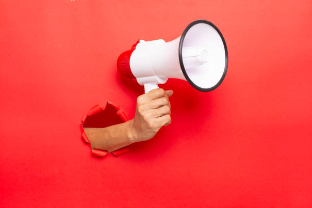 man hand holding a megaphone on red  background stock photo