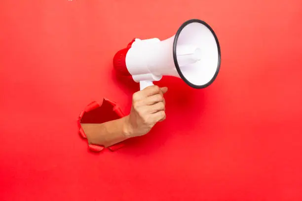 Photo of man hand holding a megaphone on red  background