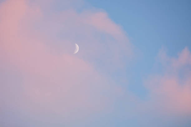 istock Half moon white on a blue sky with pink clouds 1365080323