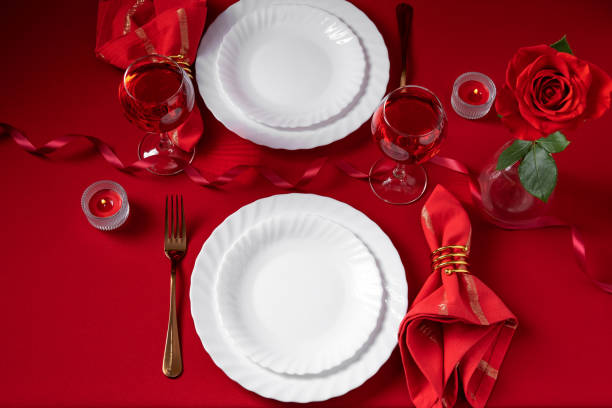 istock Romantic table setting with white dinnerware and red napkins, wine and candles. Valentines day or romantic dinner concept. Romantic Dinner. 1365081042