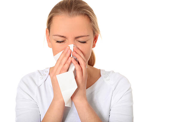 Young blonde woman blowing her nose with a tissue stock photo