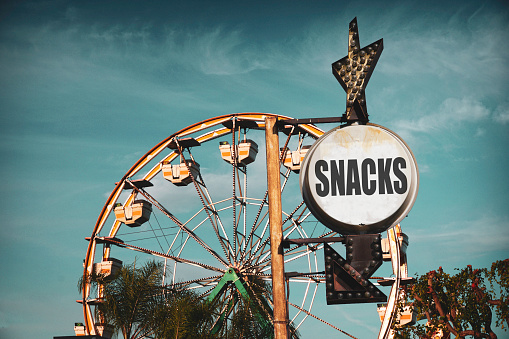 Aged and worn vintage photo of Ferris wheel and snack sign