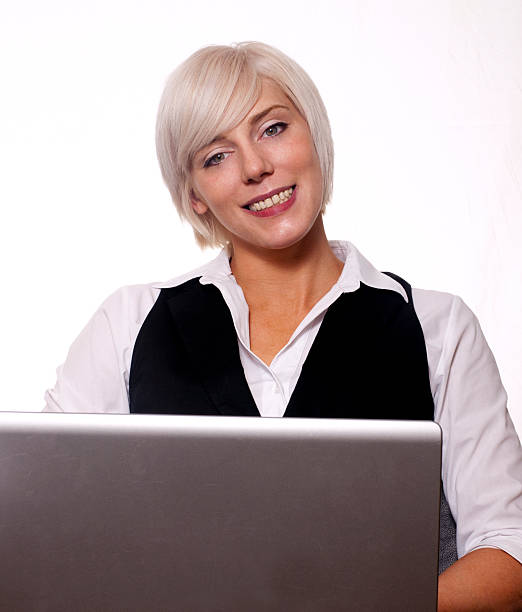 Young business woman working on laptop against white background stock photo
