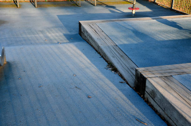 istock playground with stainless steel slide and blue rubber surface. stepped terraces bordered by massive beams. Galvanized fencing with a gate against dogs. swings on a steel spring backyard nursery in the park 1365083270