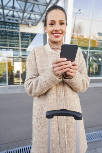 istock Positive female staring at camera while holding smartphone 1365084212