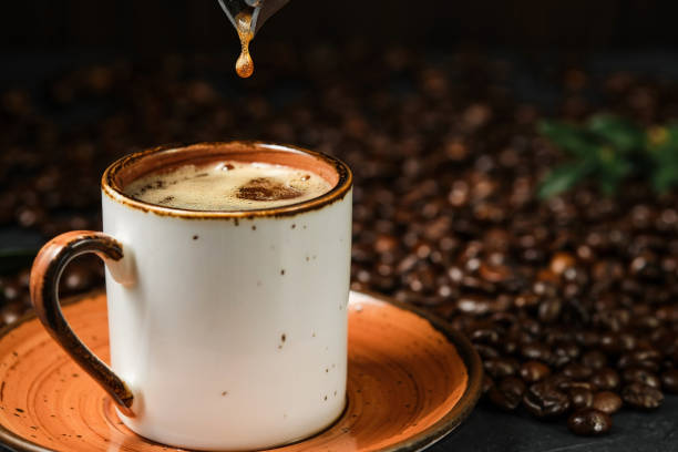 istock Espresso coffee in a white ceramic cup, close-up, selective focus. A drop of coffee falls from the coffee pot into the cup. Italian aromatic coffee for breakfast. 1365085599
