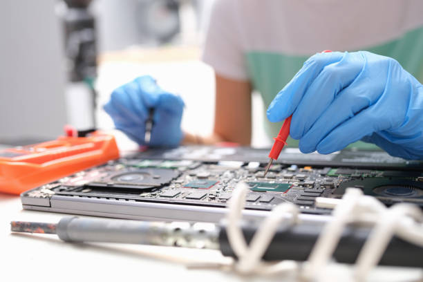 Repairman hands hold screwdrivers over laptop processor stock photo