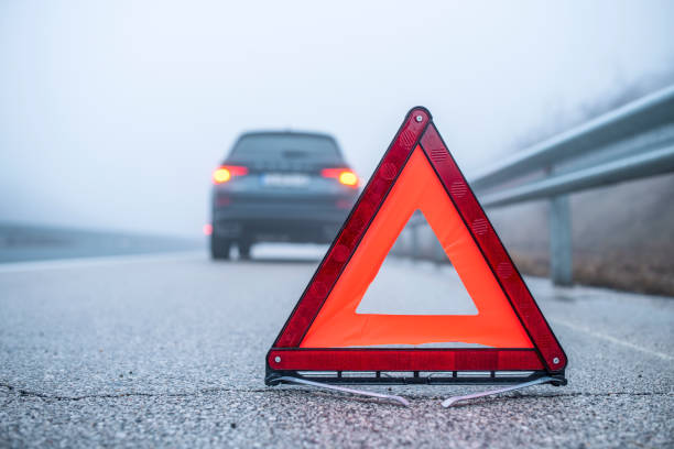 Car breakdown during foggy weather. Shot of a emergency triangle sign next to broken car. hazard sign photos stock pictures, royalty-free photos & images