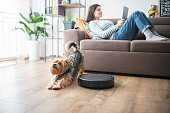 Woman and dog relaxing in the living room while robot vaccum cleans.
