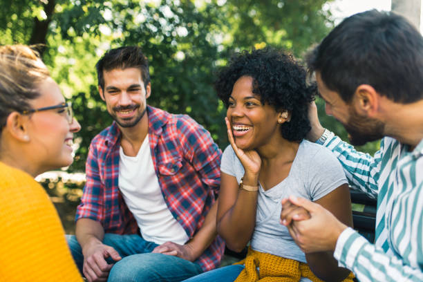 istock Woman with ear hearing problem having fun with her friends in the park 1365092424