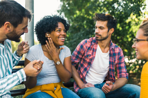 istock Woman with ear hearing problem having fun with her friends in the park 1365092432