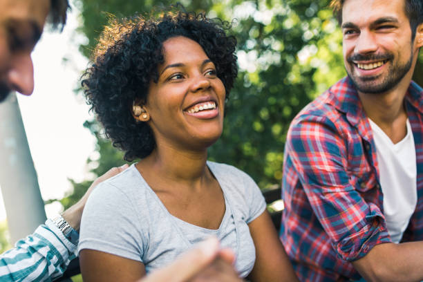 istock Woman with ear hearing problem having fun with her friends in the park 1365092597