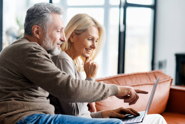 istock Serene and happy middle-aged spouses using laptop sitting on sofa 1365094220