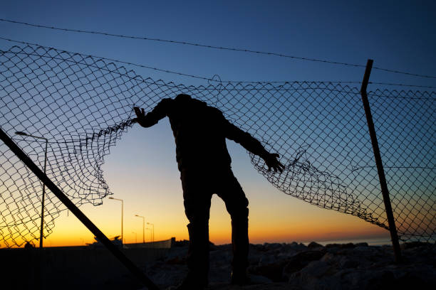 istock Refugee man running behind fence 1365094569