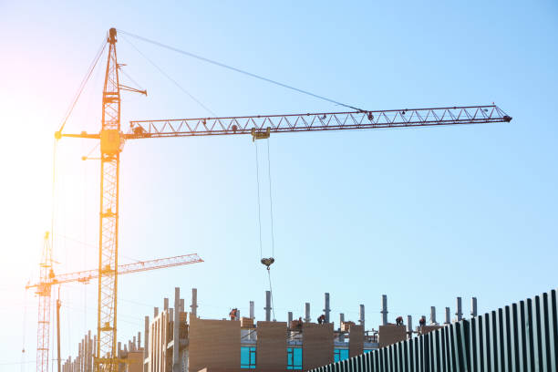 istock High rise construction crane on background of an unfinished multi storey and multi apartment residential building. 1365097491