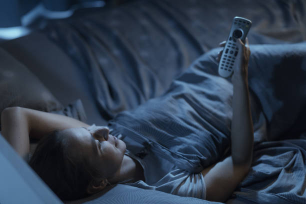 istock Woman lying in bed and watching TV 1365099790