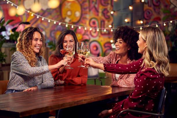 Multi-Cultural Group Of Female Friends Celebrating Making Toast Enjoying Party Night Out In Bar stock photo