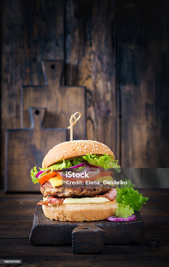 Hamburger with bacon, turkey burger meat, cheese, tomato and lettuce on wooden background. Tasty burger. Close up Burger Stock Photo