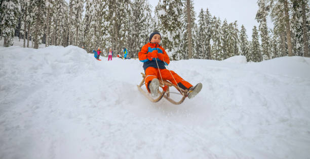 istock Boy tobogganing on snowy hill 1365101851