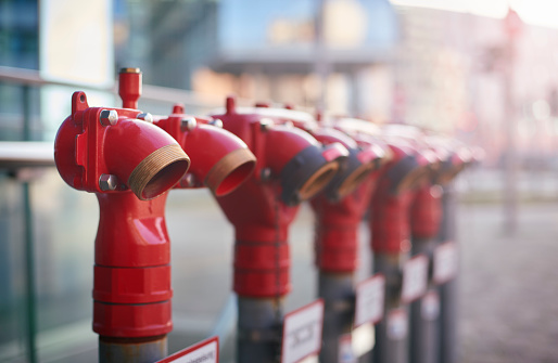 Row of modern red fire hydrants in front of office buildings.