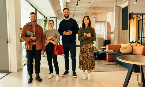istock Four businesspeople standing together in a modern office 1365105490