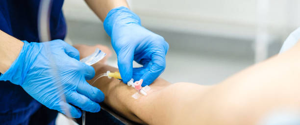 insertar la aguja gotera en el brazo del paciente. - suero fotografías e imágenes de stock