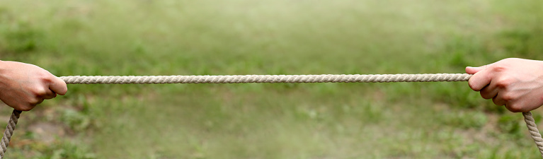 Group of business people having fun while playing tug-of-war on a break in the office.