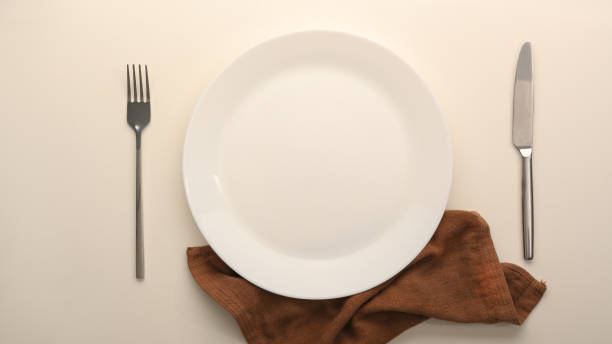 istock Top view of a blank white plate with silverware and brown napkin 1365109609