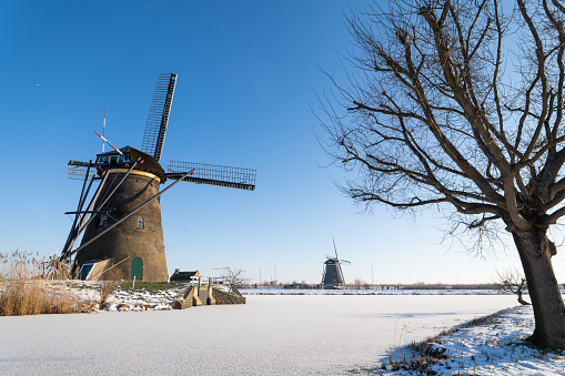 A Dutch windmill in winter conditions during sunrise. The location is Kinderdijk, the Netherlands