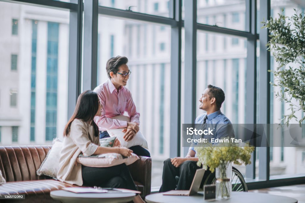 Indian male white collar worker in wheelchair discussion in office lounge with his colleague Office Stock Photo