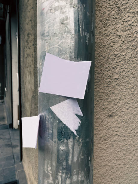 Blank paper ad on a white sheet on a street pole - street advertising White paper sheet of advertisement on a pole against the background of the Street Wall - outdoor advertising on paper sheets. Pasting of outdoor advertising ads. Postcard and bill posting concept. wild posting ad stock pictures, royalty-free photos & images
