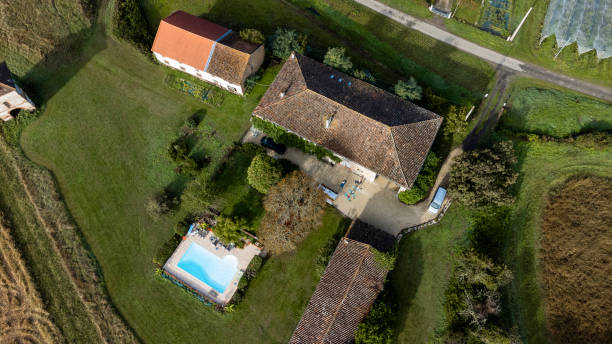 A drone point of view, aerial view, wide shot of a vacation rental home in Castelferrus, France. There are three buildings and a swimming pool. The house is occupied by guests.