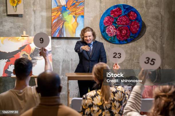 Male Auctioneer Pointing At One Of People With Auction Paddles Stock Photo - Download Image Now