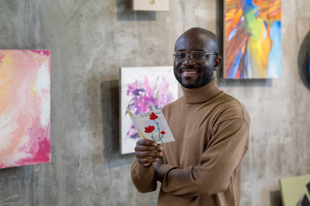 istock Cheerful young African man with leaflet looking at you 1365119138