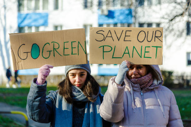 istock Activists holding signs protesting against climate change on city street 1365119823