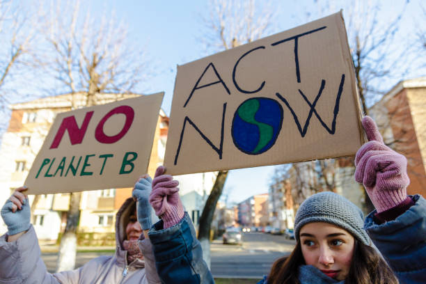istock Activists holding signs protesting against climate change on city street 1365119834