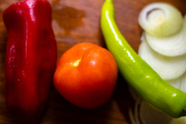 istock Wooden board, tomatoes, onions, peppers, knife 1365123825
