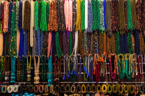 A range of colorful Handicraft bead necklaces and bangles hanging from the string in a shop. Close up shot of the colorful jewels.