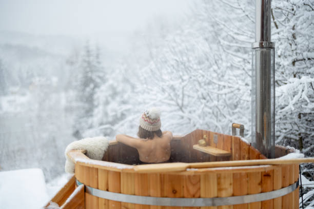 Woman relaxing in hot bath at snowy mountains Woman relaxing in hot bath outdoors, sitting back and enjoying beautiful view on snowy mountains. Winter holidays in the mountains, hot water treatments concept. Caucasian woman wearing winter hat thermal pool stock pictures, royalty-free photos & images