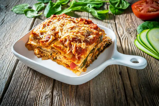 Protein rich Lasagna Vegan Italian food plant based recipe Mediterranean diet with ingredients as Lasagna pasta, onion, mushrooms, zucchini, bell pepper, spinach, vegan marinara sauce, tomatoes, firm tofu, chick peas, vegan cheese