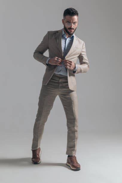 istock sexy young man with eyeglasses buttoning jacket and looking down 1365129130