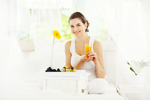 Woman drinking orange juice as a breakfast in bed